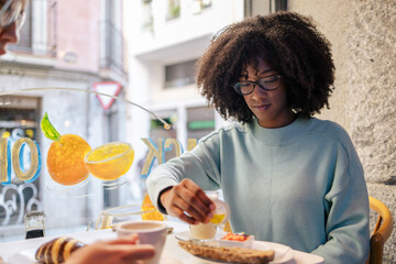 Two diverse friends having breakfast in cafeteria