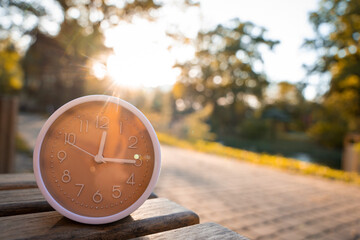 The clock stands on a bench in the park on a sunny autumn day. Change time concept. Planning your...