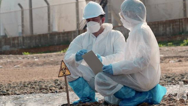 Ecologist sampling taken dead fish to inspaction and save data to laptop computer, Biologist wear protective suit and mask collects sample of waste water from industry, problem environment