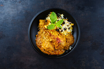 Traditional spicy Indian chicken Madras curry Rogan Josh with drumsticks and rice served as top view in a Nordic design bowl with copy space