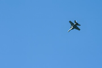 F/A-18 Hornet military jet soaring in a clear blue sky.