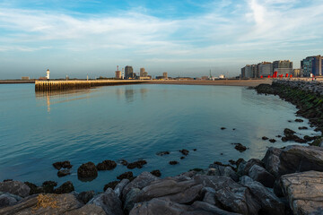 Pier and lighthouse with modern apartment buildings at sunset, Oostende, West Flanders, Belgium.