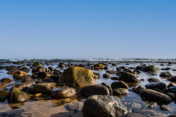 Sea water laps the rocks on the stone beach.