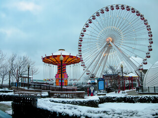 Snowy day at Navy Pier, Chicago with a lit Ferris wheel and carousel in view.