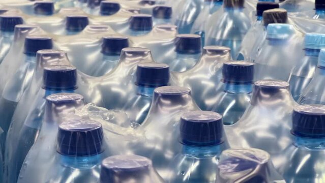Mineral water in two-liter bottles packed in 6 bottles stand in warehouse. Long shot