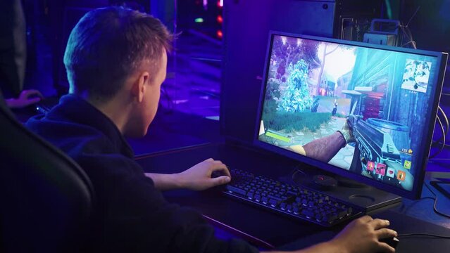 Gamer having fun in the casual first person shooter video game on a computer display. Gamer playing the shooter simulator on a modern display. Gamer winning the shooter round. Gaming display.