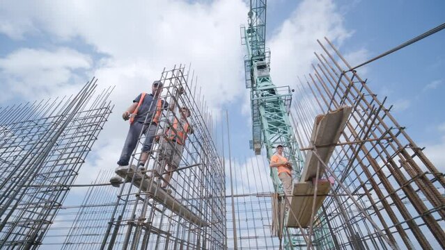 A worker uses steel tying wire to fasten steel rods to reinforcement bars. Reinforced concrete structures - knitting of a metal reinforcing cage.
