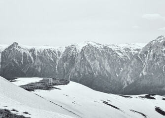Obraz premium Scenic view from Baiului Mountains with the snowy peaks of Bucegi Mountains. Carpathians in Romania. Black and white photography.