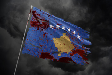 Kosovo torn flag on dark sky background with blood stains.