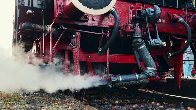 Pipe of old historic German locomotive releases thick clouds of steam