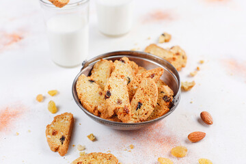 Italian raisin almond biscotti and glass of milk on light background.