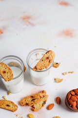 Italian raisin almond biscotti and glass of milk on light background.