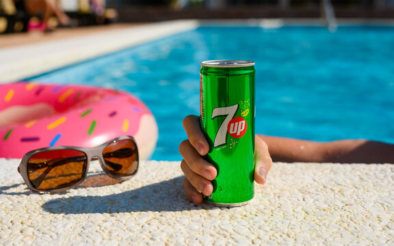 Anapa, Russia - July 18, 2023: The hand of a vacationing tourist reaches for a cold can of 7up by the pool. Summer relaxation by the pool. Close-up, selective focus