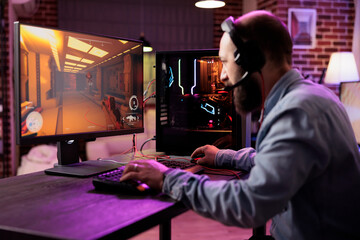 Gamer using expert grade level gaming computer to avoid disruptive lag while playing esports competitions. Man relaxing at home playing action shooter videogame late at night