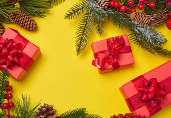 Christmas decor, gifts wrapped in red paper on a yellow background, top view.