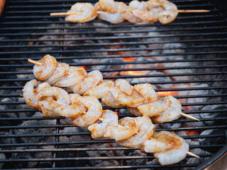 Shrimp skewers grilling on a bbq outside 