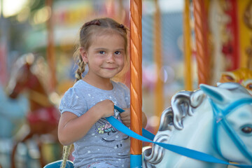 baby girl on a carousel in an amusement park © justoomm
