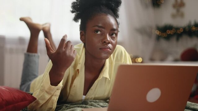 Portrait of pretty creative african american woman student thinks questioningly about difficult choice choose imagine plan in mind has doubts create idea at desk laying on bed at home