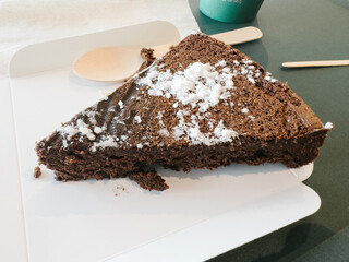 Delicious cake covered with sugar powder, presented on a table with a wooden spoon nearby.