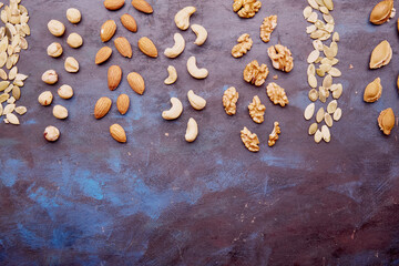 Food snacks rustic background with assorted nuts. Hazelnuts , walnuts, almonds, cashews. Copy space.