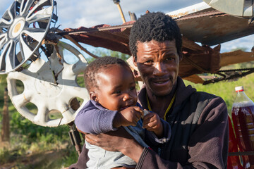 african village ,street vendor selling petrol gas in bottles by the side of the road, he is holding...