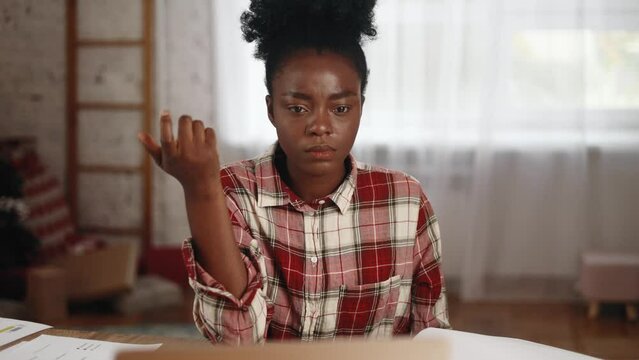 Portrait of pretty creative african american woman student thinks questioningly about difficult choice choose imagine plan in mind has doubts create idea at desk next to laptop at home workplace