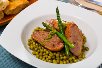 Delicious duck breast with steamed asparagus and canned green peas