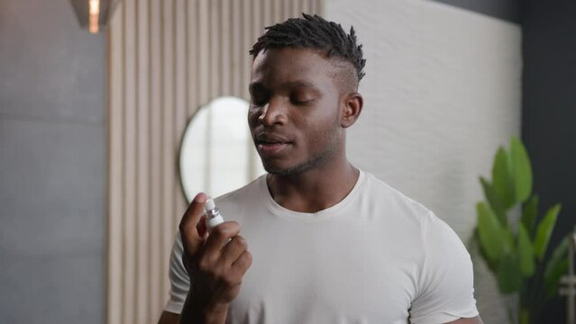 African American ethnic man applying fresh breath spray prevent stink morning hygiene of mouth preparing for date in bathroom smiling guy spraying freshener oral dental care product refresh breathing