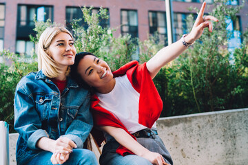 Happy multiracial girlfriends resting after shopping in street