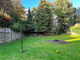 Tranquil garden, with a washing line, a football,  flowering bushes, and old trees, on a late summers day in, Bradford, UK