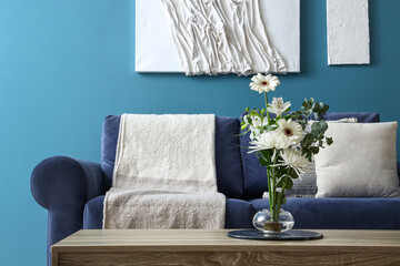 Interior of living room with ikebana on table and blue sofa