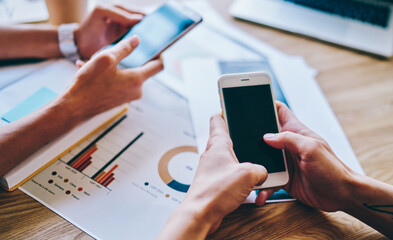Colleagues surfing smartphones in office space