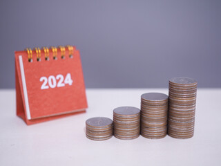 2024 desk calendar with stack of coins. The concept of saving money, Financial, Investment and...