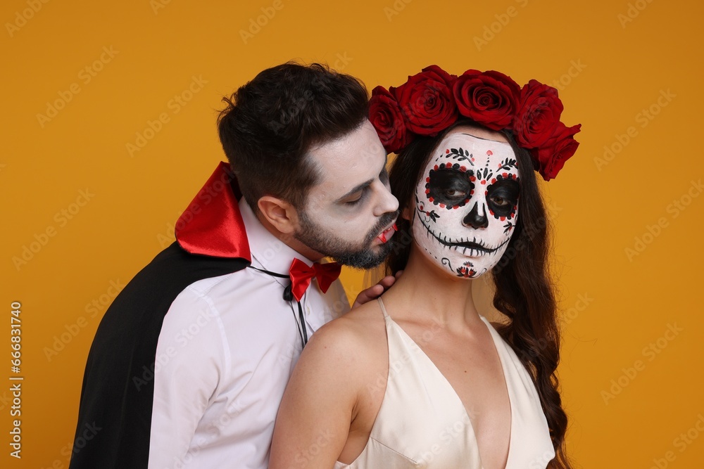 Poster couple in scary bride and vampire costumes on orange background. halloween celebration