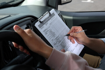 Driving school. Student passing driving test with examiner in car, closeup - obrazy, fototapety, plakaty