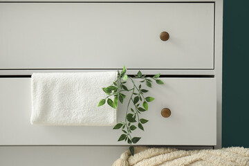 Opened drawer with clean towel and artificial plant, closeup