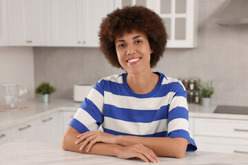 Fototapeta premium Happy young woman sitting at table in kitchen