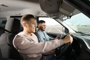 Driving school. Happy student passing driving test with examiner in car at parking lot