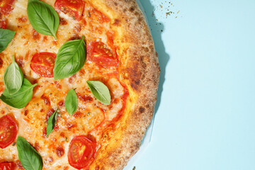 Tasty pizza Margarita with tomatoes and basil on blue table
