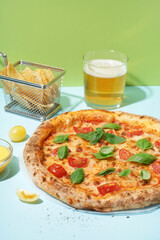 Tasty pizza Margarita with basil and glass of beer on blue table