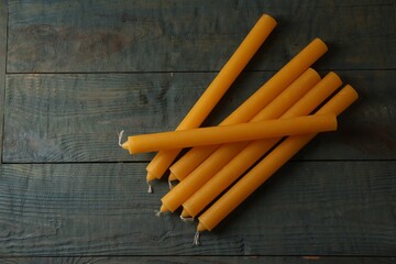 Many church wax candles on old wooden table, flat lay