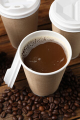 Coffee to go. Paper cups with tasty drink and beans on wooden table, closeup
