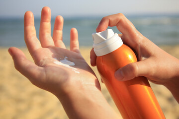 Child applying sunscreen near sea, closeup. Sun protection care - obrazy, fototapety, plakaty