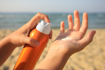 Child applying sunscreen near sea, closeup. Sun protection care - obrazy, fototapety, plakaty
