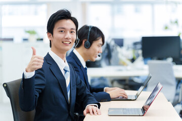 コールセンターでサムアップをする男性