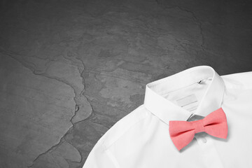 White shirt with stylish coral bow tie on grey background, top view. Space for text