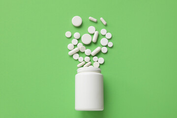 Jar with scattered pills on green background - obrazy, fototapety, plakaty