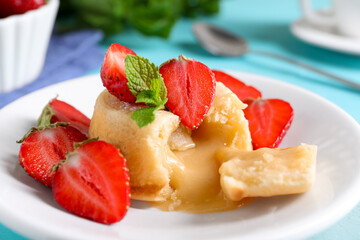 Tasty vanilla fondant with white chocolate and strawberries on table, closeup