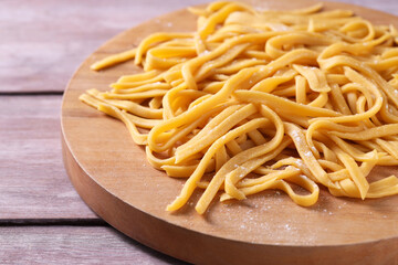 Board with homemade pasta on wooden table, closeup