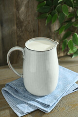 Jug of fresh milk on wooden table